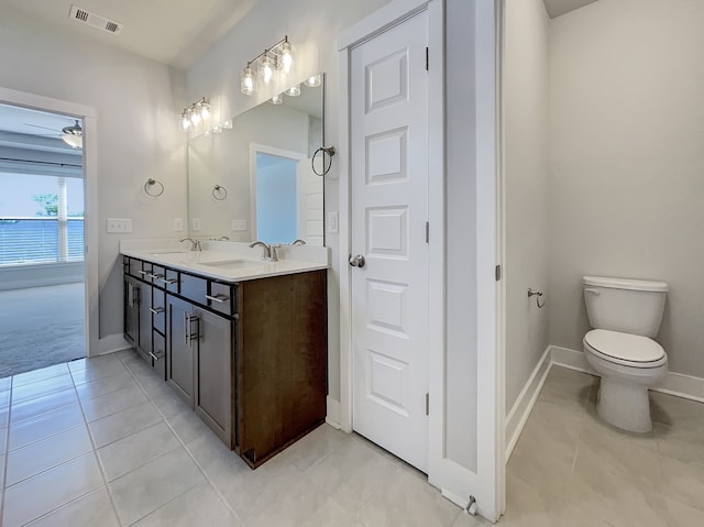 bathroom featuring toilet, tile floors, ceiling fan, and dual vanity