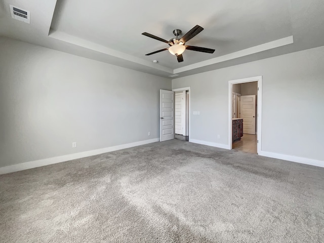 carpeted spare room with ceiling fan and a tray ceiling