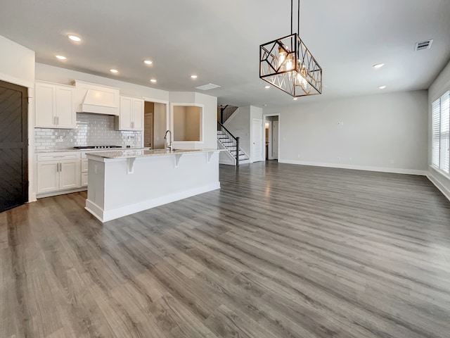 kitchen featuring wood-type flooring, an island with sink, a kitchen breakfast bar, and pendant lighting