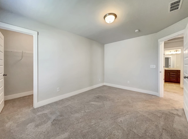 unfurnished bedroom featuring a closet, a spacious closet, and light carpet