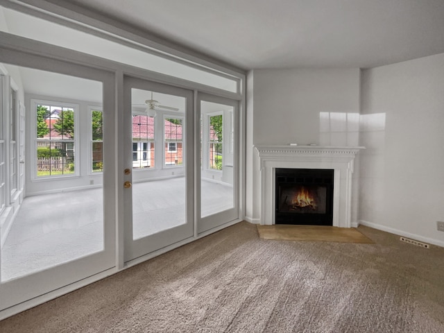 unfurnished living room featuring french doors, ceiling fan, and carpet