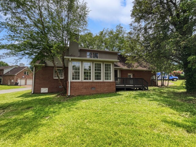 back of property with a garage, a deck, and a lawn