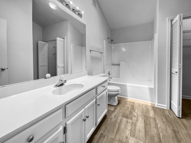 full bathroom with wood-type flooring, vanity, tub / shower combination, and toilet