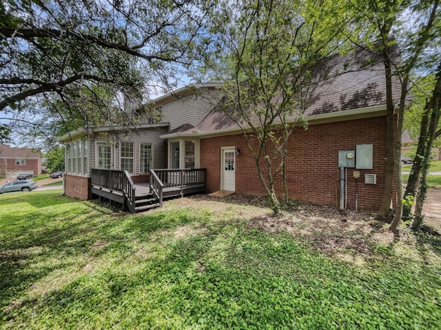 rear view of property with a wooden deck and a lawn