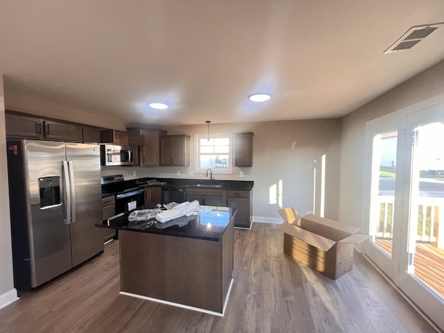 kitchen featuring stainless steel appliances, sink, wood-type flooring, pendant lighting, and a kitchen island