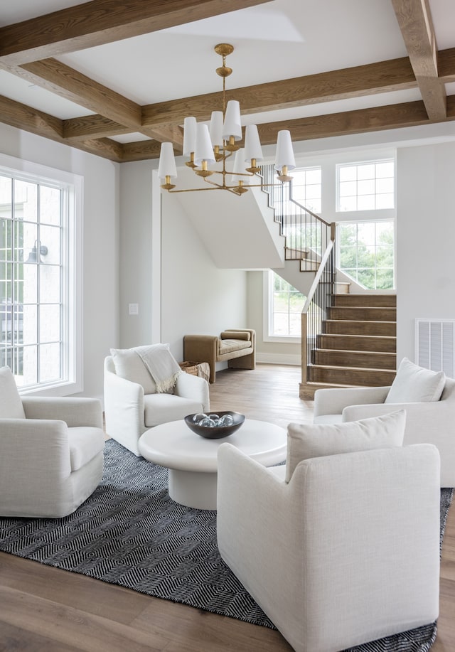 living room featuring beam ceiling, hardwood / wood-style flooring, and a notable chandelier