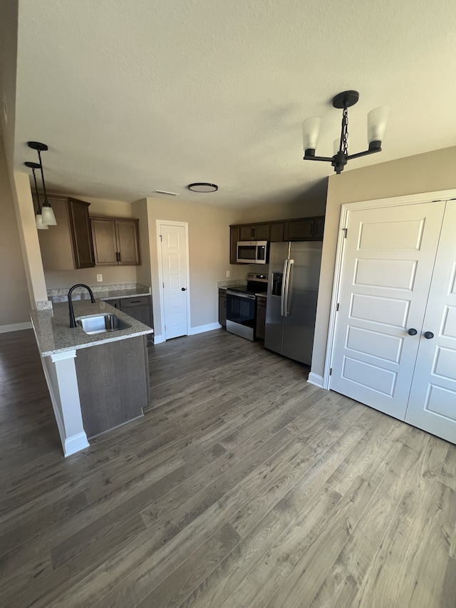 kitchen featuring pendant lighting, sink, dark hardwood / wood-style floors, and appliances with stainless steel finishes