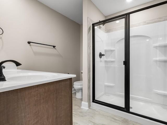 bathroom featuring vanity, a shower with shower door, and toilet