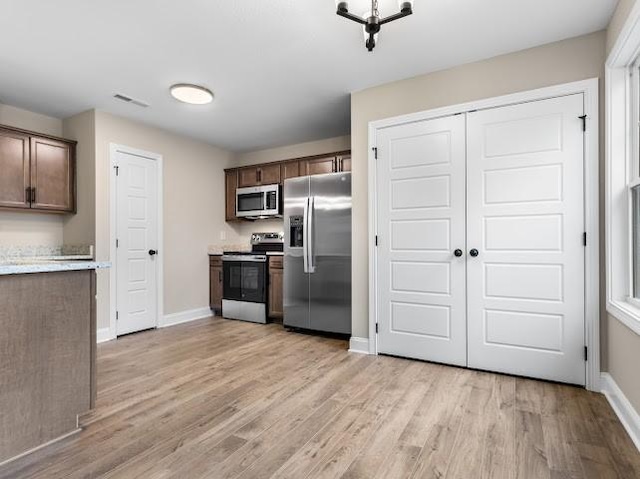 kitchen with appliances with stainless steel finishes, dark brown cabinetry, and light hardwood / wood-style flooring