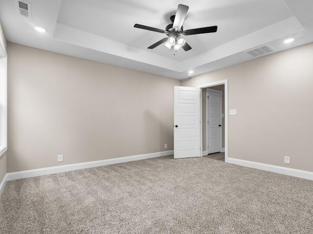 unfurnished room with ceiling fan, carpet flooring, and a tray ceiling