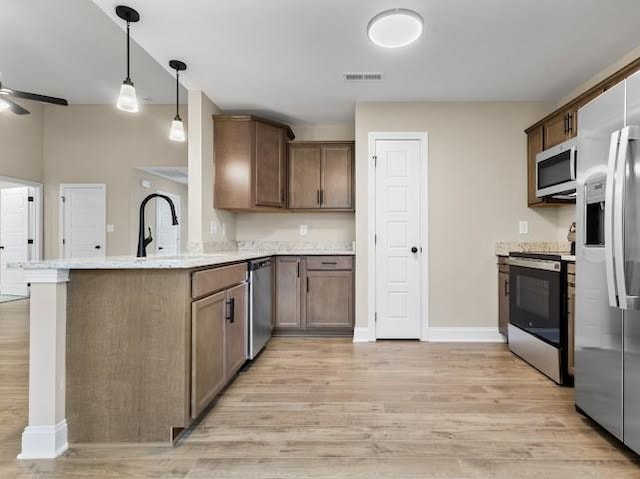 kitchen with hanging light fixtures, appliances with stainless steel finishes, kitchen peninsula, ceiling fan, and light hardwood / wood-style floors