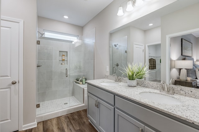 bathroom featuring wood-type flooring, a shower with door, large vanity, and double sink