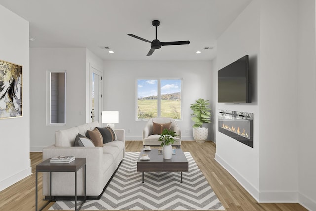 living room with ceiling fan and light hardwood / wood-style flooring