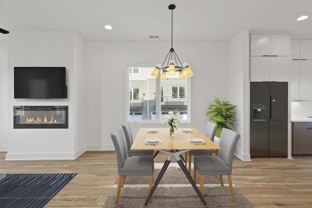 dining area with a notable chandelier and light hardwood / wood-style flooring