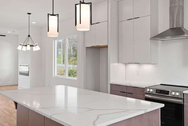 kitchen featuring light stone countertops, white cabinetry, hanging light fixtures, wall chimney range hood, and stainless steel range with electric cooktop