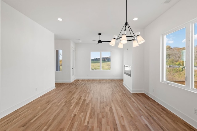 unfurnished dining area with light hardwood / wood-style flooring and ceiling fan with notable chandelier