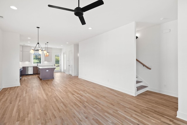 unfurnished living room featuring light wood-type flooring, ceiling fan, and sink