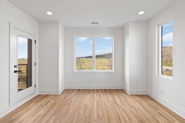 empty room with light hardwood / wood-style floors and plenty of natural light