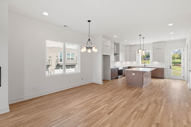 kitchen with electric range, light hardwood / wood-style floors, a kitchen island, and plenty of natural light