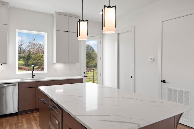 kitchen with pendant lighting, stainless steel dishwasher, sink, and a wealth of natural light