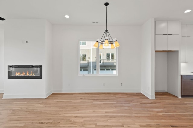 1016 W Trinity Ln Unit 1, Nashville, TN 37218 - unfurnished living room with light wood-type flooring, recessed lighting, a chandelier, and a glass covered fireplace