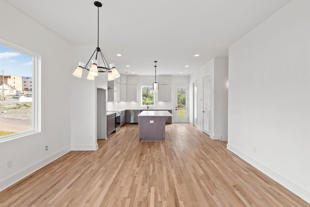 kitchen featuring dishwasher, light hardwood / wood-style flooring, a notable chandelier, decorative light fixtures, and a kitchen island