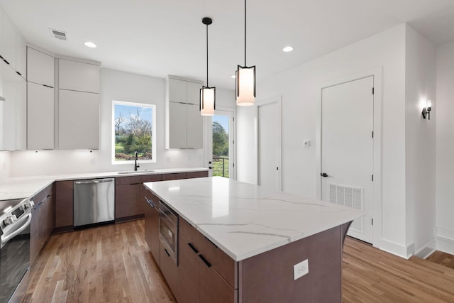 1016 W Trinity Ln Unit 1, Nashville, TN 37218 - kitchen featuring appliances with stainless steel finishes, modern cabinets, light wood-type flooring, a kitchen island, and white cabinetry