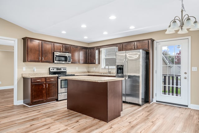 kitchen featuring dark brown cabinets, appliances with stainless steel finishes, pendant lighting, a center island, and light wood-type flooring