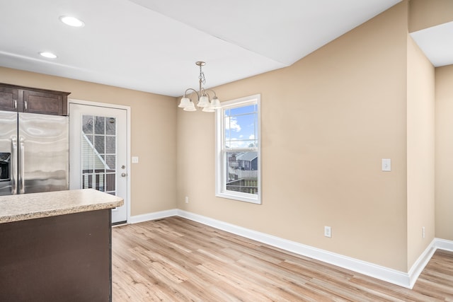 kitchen with decorative light fixtures, light hardwood / wood-style flooring, dark brown cabinets, a notable chandelier, and stainless steel fridge with ice dispenser