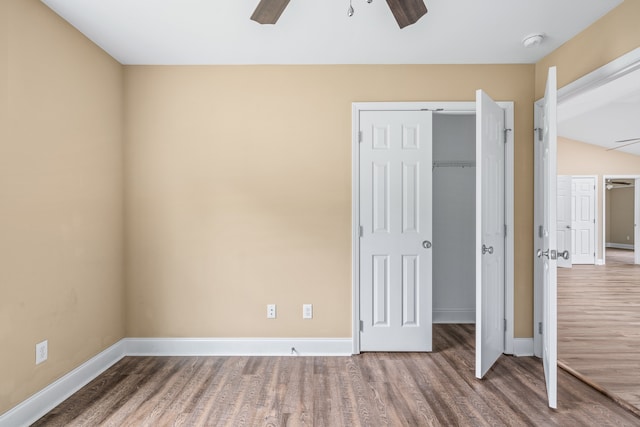 unfurnished bedroom featuring a closet, lofted ceiling, hardwood / wood-style floors, and ceiling fan