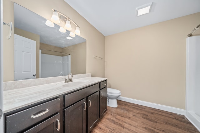 bathroom with toilet, vanity with extensive cabinet space, and hardwood / wood-style flooring