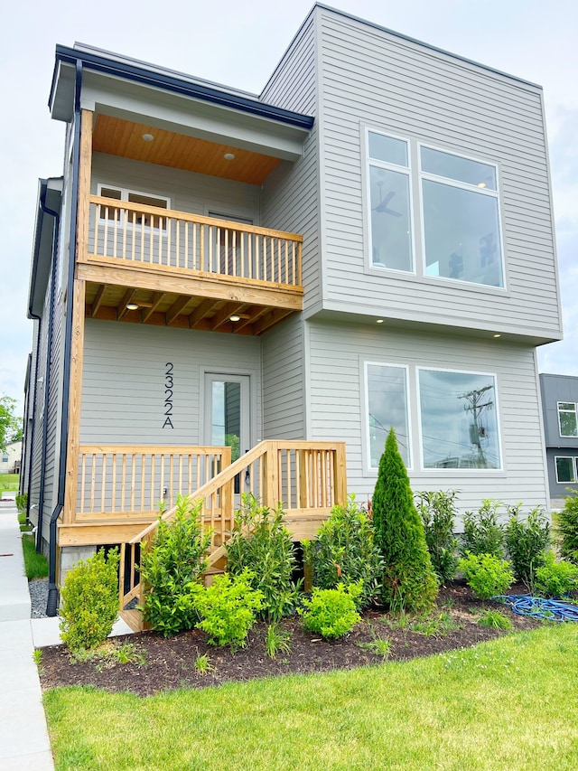 back of property with a balcony and a lawn