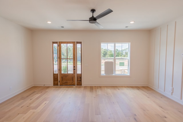 empty room with a wealth of natural light, ceiling fan, and light wood-type flooring