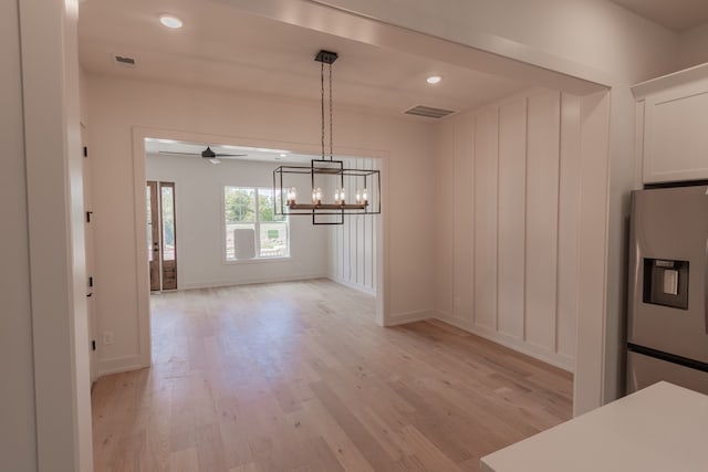 unfurnished dining area featuring light hardwood / wood-style floors and a notable chandelier