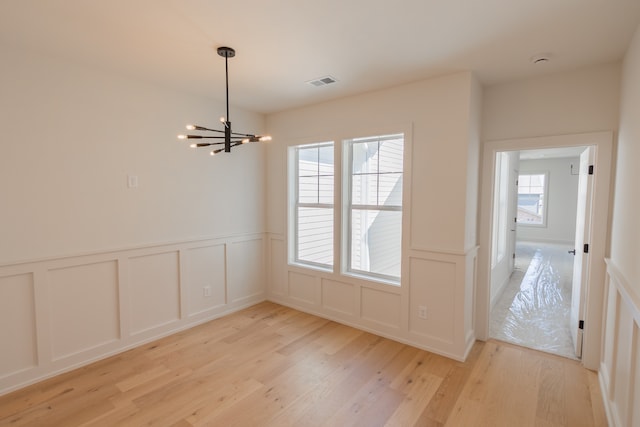 unfurnished dining area with a notable chandelier and light hardwood / wood-style floors