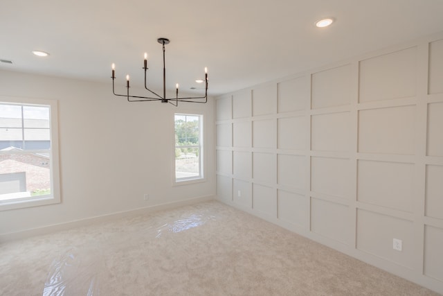 carpeted empty room featuring a notable chandelier