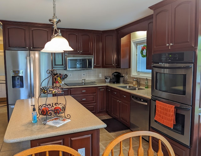 kitchen with tasteful backsplash, black appliances, sink, light tile floors, and pendant lighting