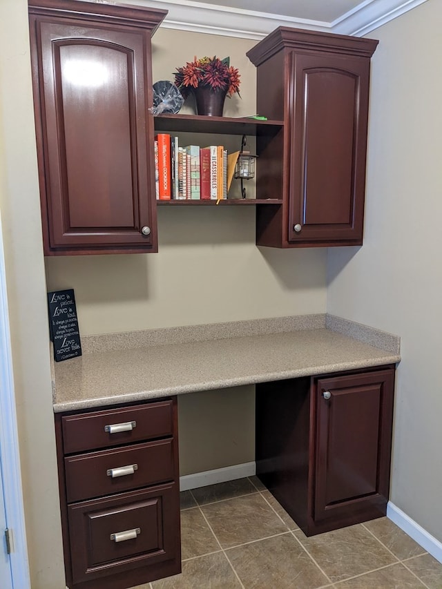 unfurnished office featuring built in desk, tile floors, and ornamental molding