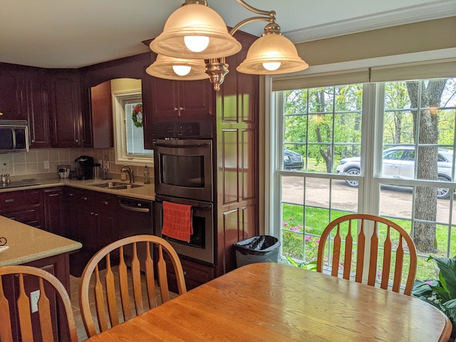 kitchen with crown molding, tasteful backsplash, pendant lighting, black appliances, and sink