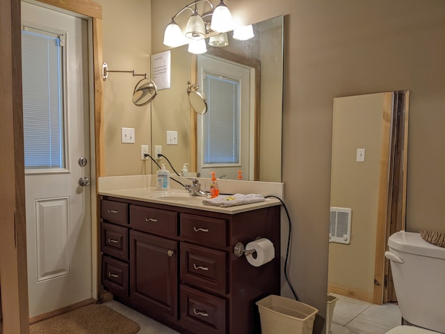 bathroom with tile flooring, an inviting chandelier, toilet, and vanity