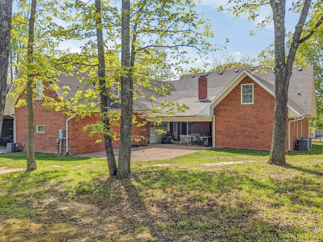 rear view of property with a patio, a lawn, and central AC