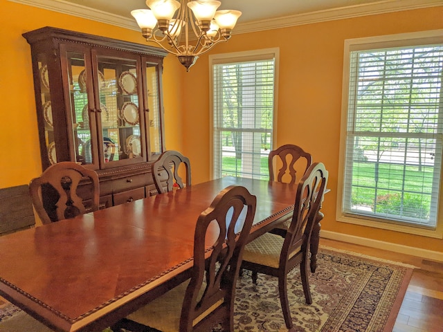 dining room featuring ornamental molding, a healthy amount of sunlight, hardwood / wood-style floors, and a chandelier