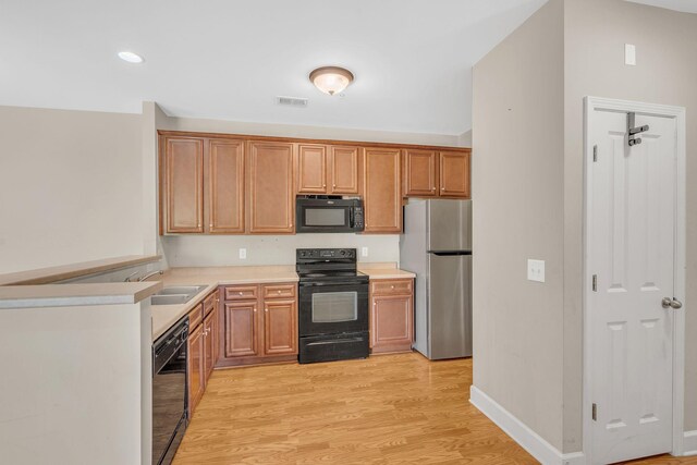 kitchen featuring light hardwood / wood-style floors, sink, and black appliances