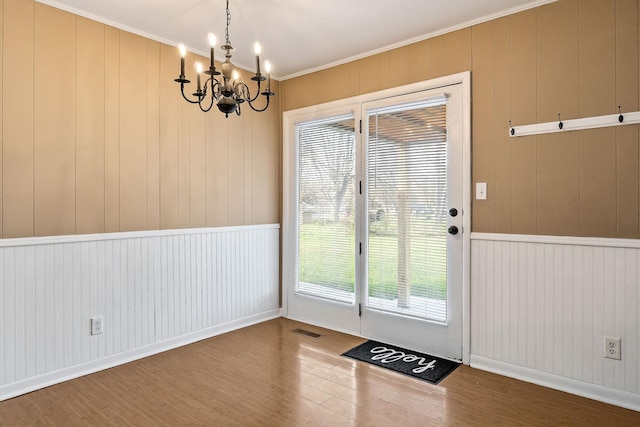 entryway featuring crown molding, wood-type flooring, and an inviting chandelier