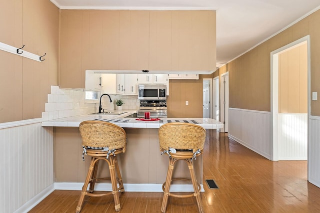 kitchen featuring stove, crown molding, sink, a kitchen bar, and kitchen peninsula