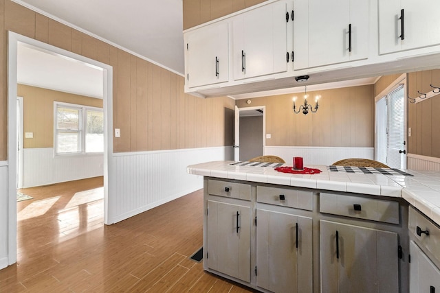 kitchen with pendant lighting, white cabinetry, tile counters, and a notable chandelier