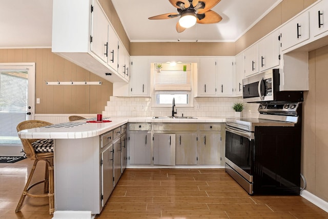 kitchen with a kitchen breakfast bar, white cabinetry, sink, and appliances with stainless steel finishes