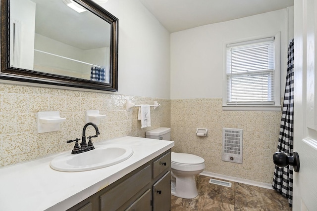 bathroom with vanity, toilet, tile walls, and heating unit