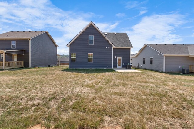 rear view of property featuring cooling unit, a lawn, and a patio area