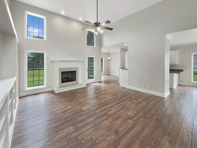 unfurnished living room with dark hardwood / wood-style flooring, a towering ceiling, and a fireplace